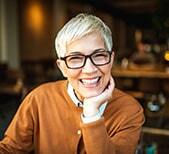 Smiling dentist wearing glasses and brown shirt in Niceville dental practice.