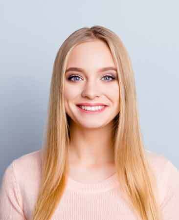 Smiling woman with long blonde hair in light pink top for Niceville dental practice.