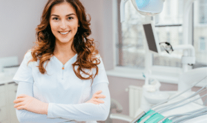 Female dental professional in white coat with arms crossed, smiling in modern dental office in Niceville, Florida.