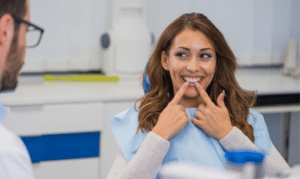 Woman smiling and pointing to her teeth during a dental consultation with a dentist.