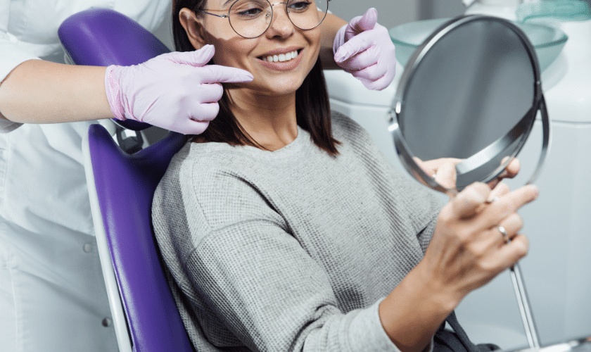 Female patient smiling at mirror during dental checkup with dentist in Niceville, FL.