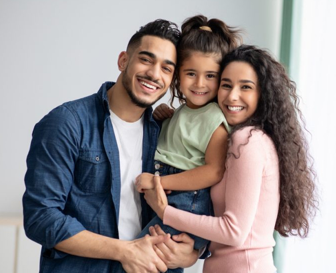 Young family smiling together at Niceville dental practice.
