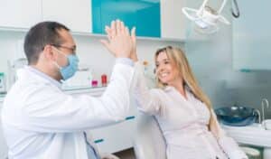 Dentist and patient giving high five in modern dental office in Niceville.