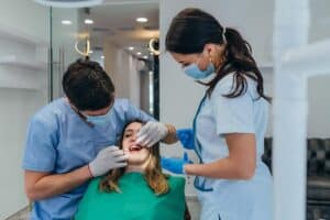 Dental team examining patient's teeth during urgent care appointment in Niceville office.