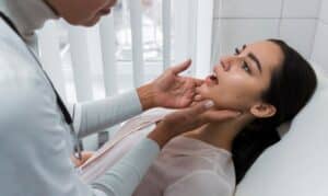 Dentist examining a patient's jaw and throat during a tongue tie assessment in Niceville, FL.