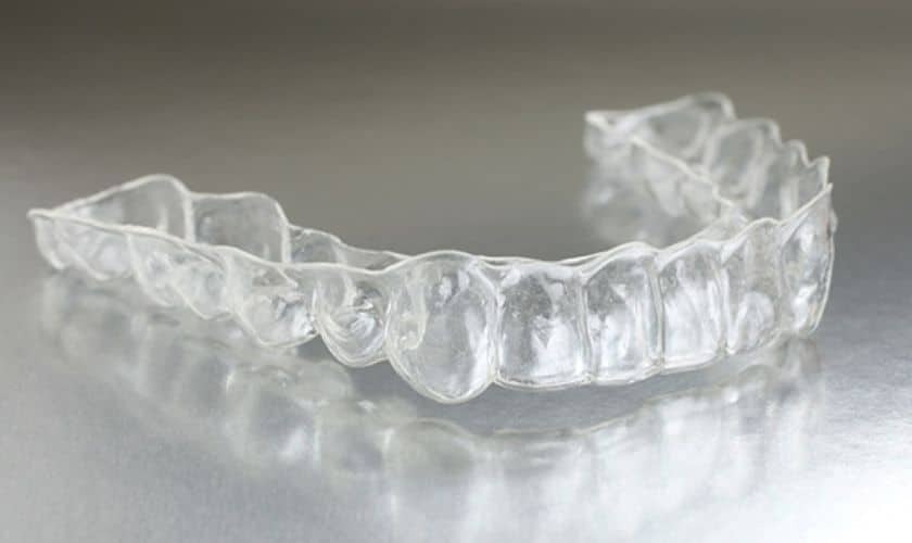Clear Invisalign retainer tray displayed against a neutral background, showing the transparent dental aligner used for teen.