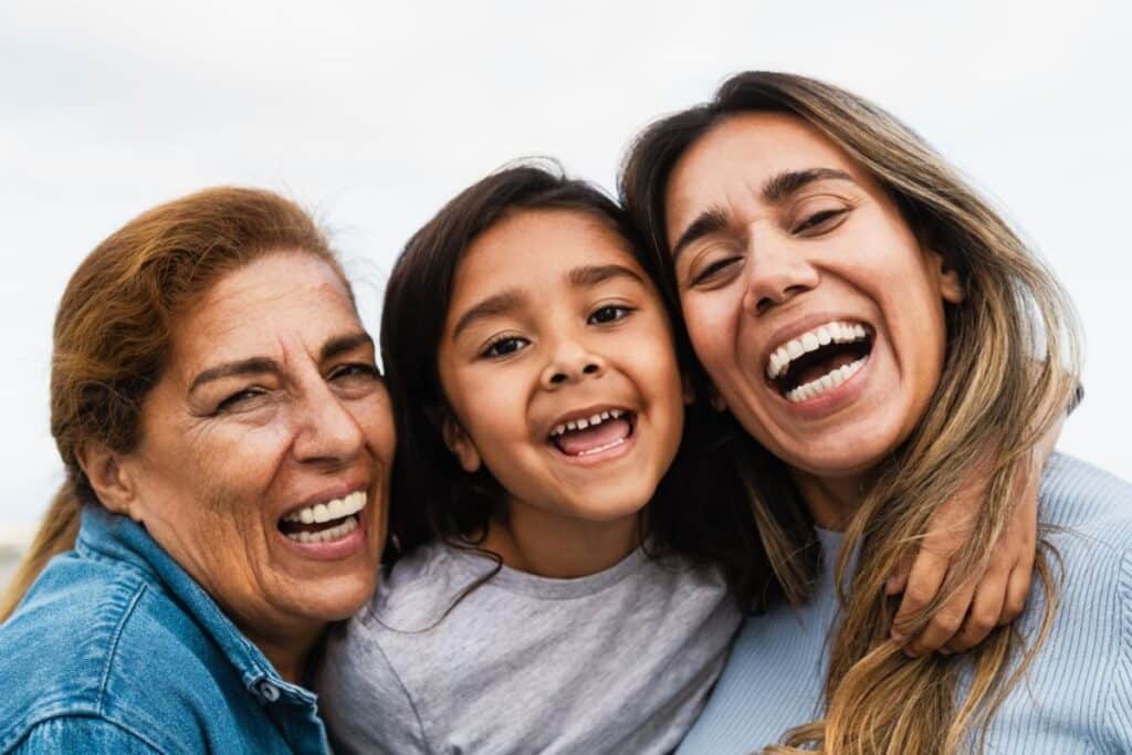 Happy family of three generations smiling together, representing dental health for all ages.