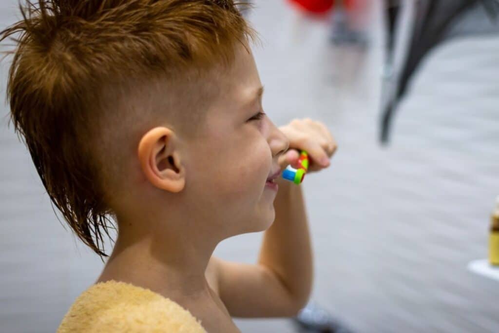 Young boy holding a colorful toy while smiling, demonstrating positive dental health habits for kids.