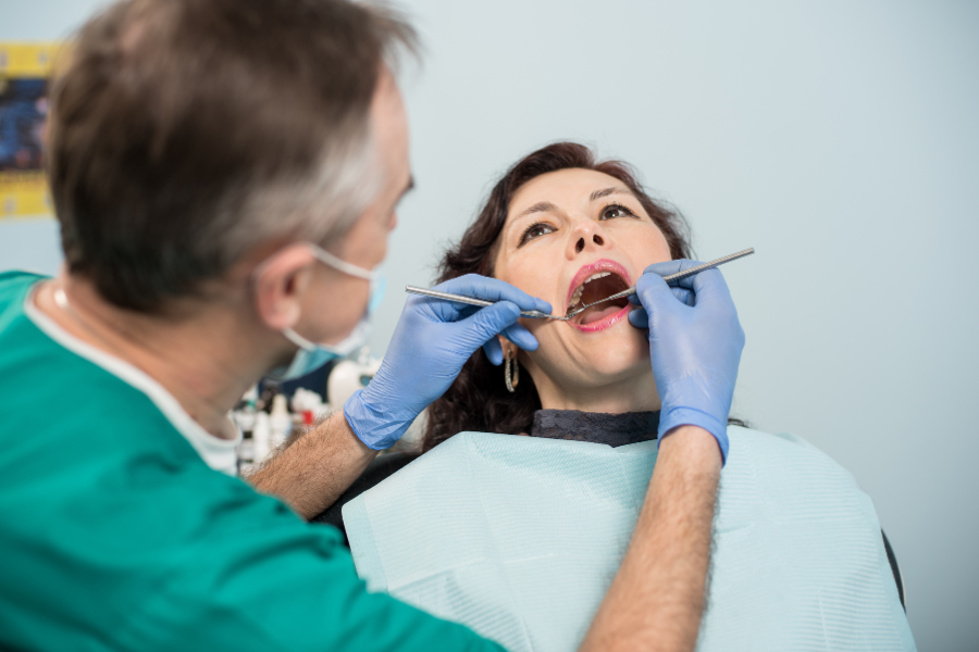 Dentist examining patient's teeth during oral exam in dental office.